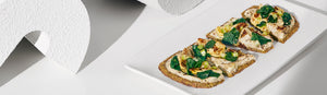 Artichoke + Spinach Flatbread cut into four pieces on a white plate