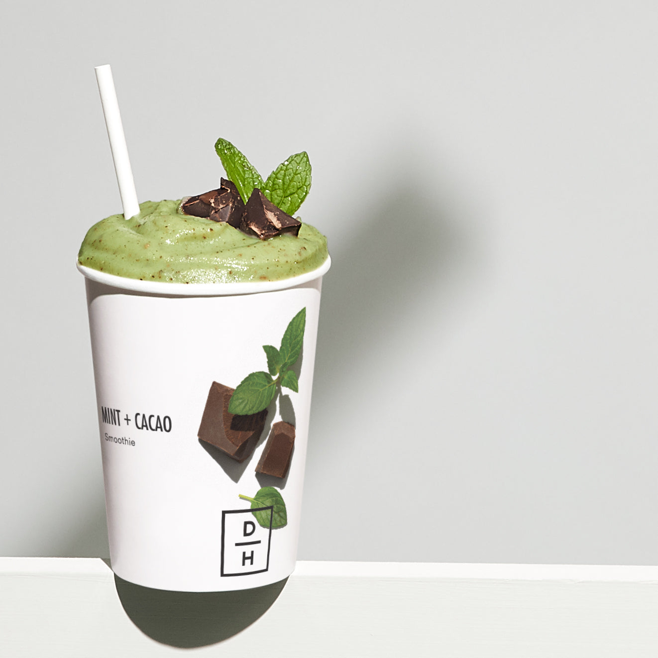 Daily Harvest Mint + Cacao Smoothie prepared in a cup with mint and cacao garnish.