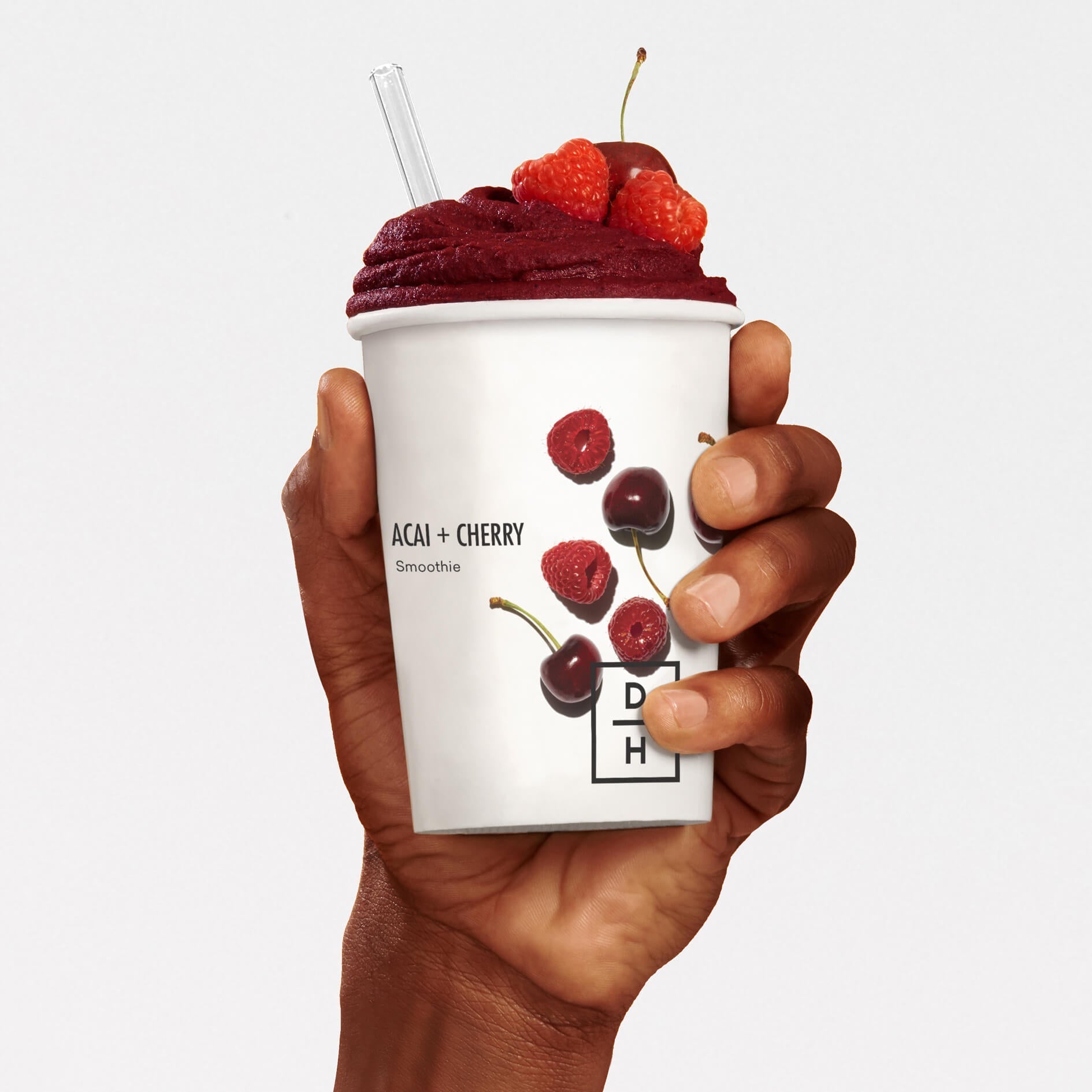 A hand holding a prepared Daily Harvest Acai + Cherry Smoothie with garnish.