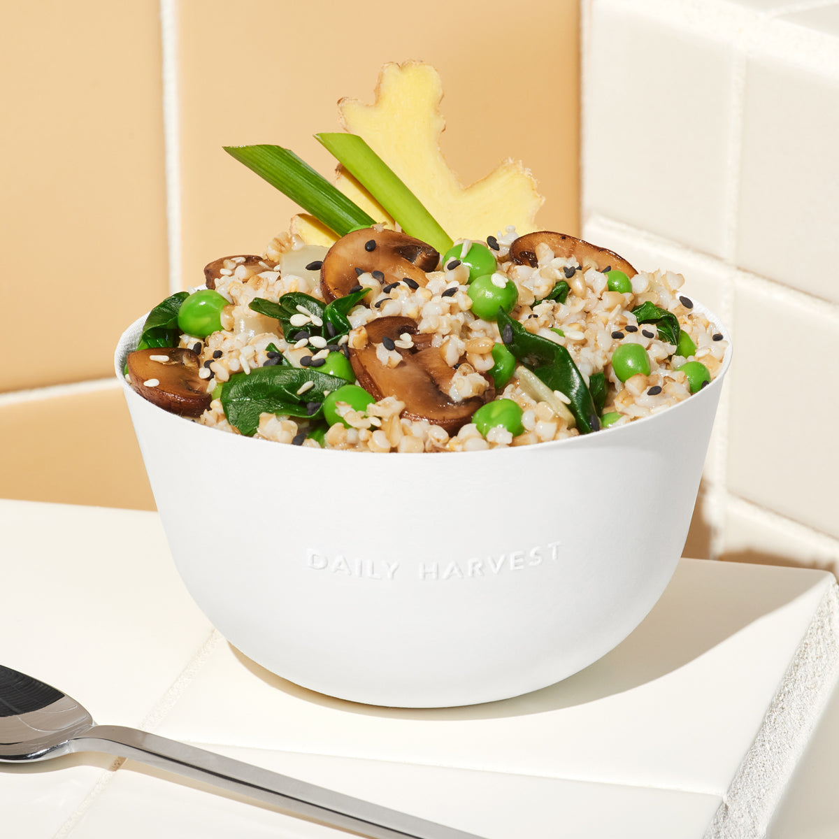 Lifestyle image of Daily Harvest Cremini + Miso Oat Forager Bowl prepared in a bowl alongside a spoon.