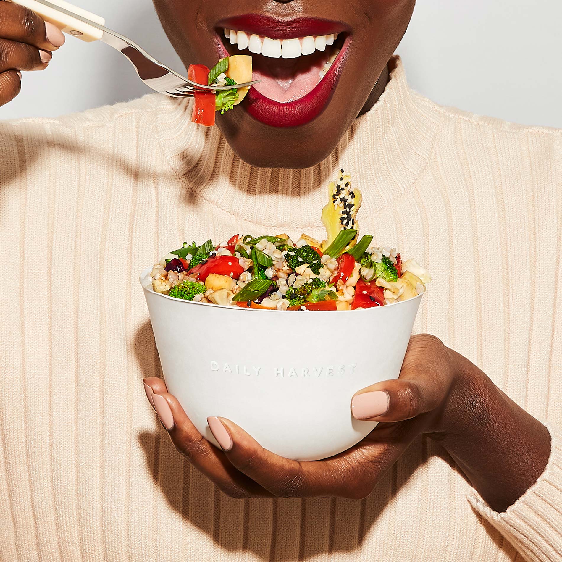 A person eating Daily Harvest Broccoli + Tamari Sesame Harvest Bowl with a fork.