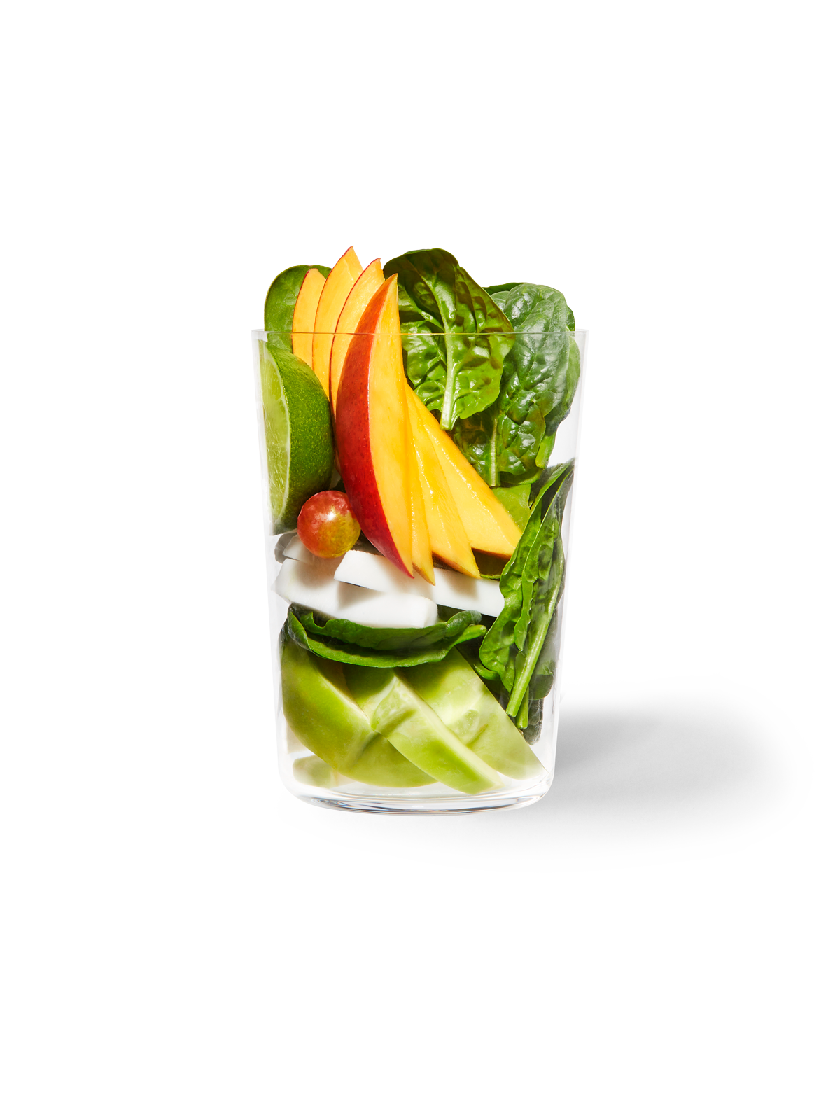 Clear cup filled with the ingredients included in our Daily Harvest Mango + Greens Smoothie.