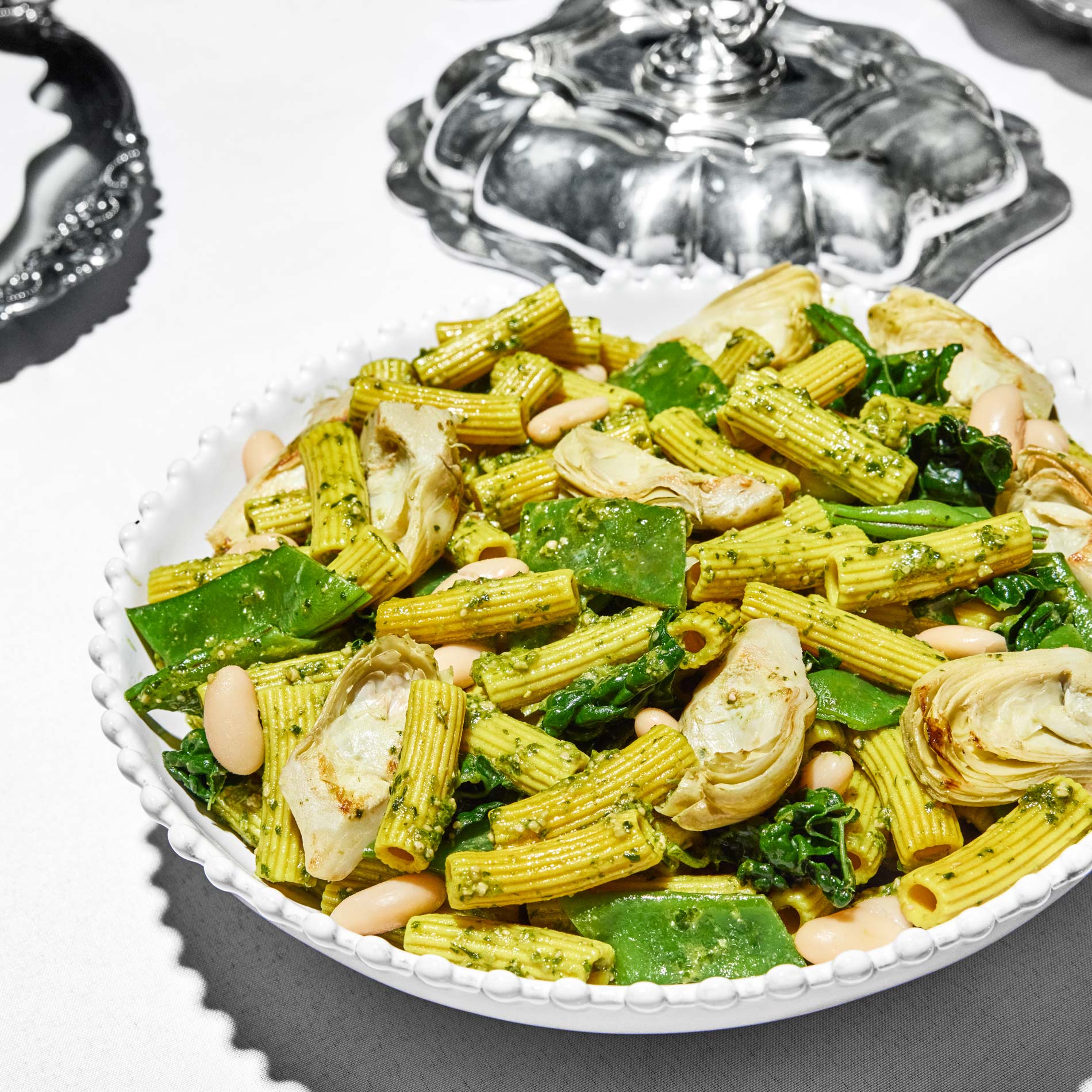 The Daily Harvest’s White Bean + Spinach Pesto Pasta on a serving bowl on a set table.