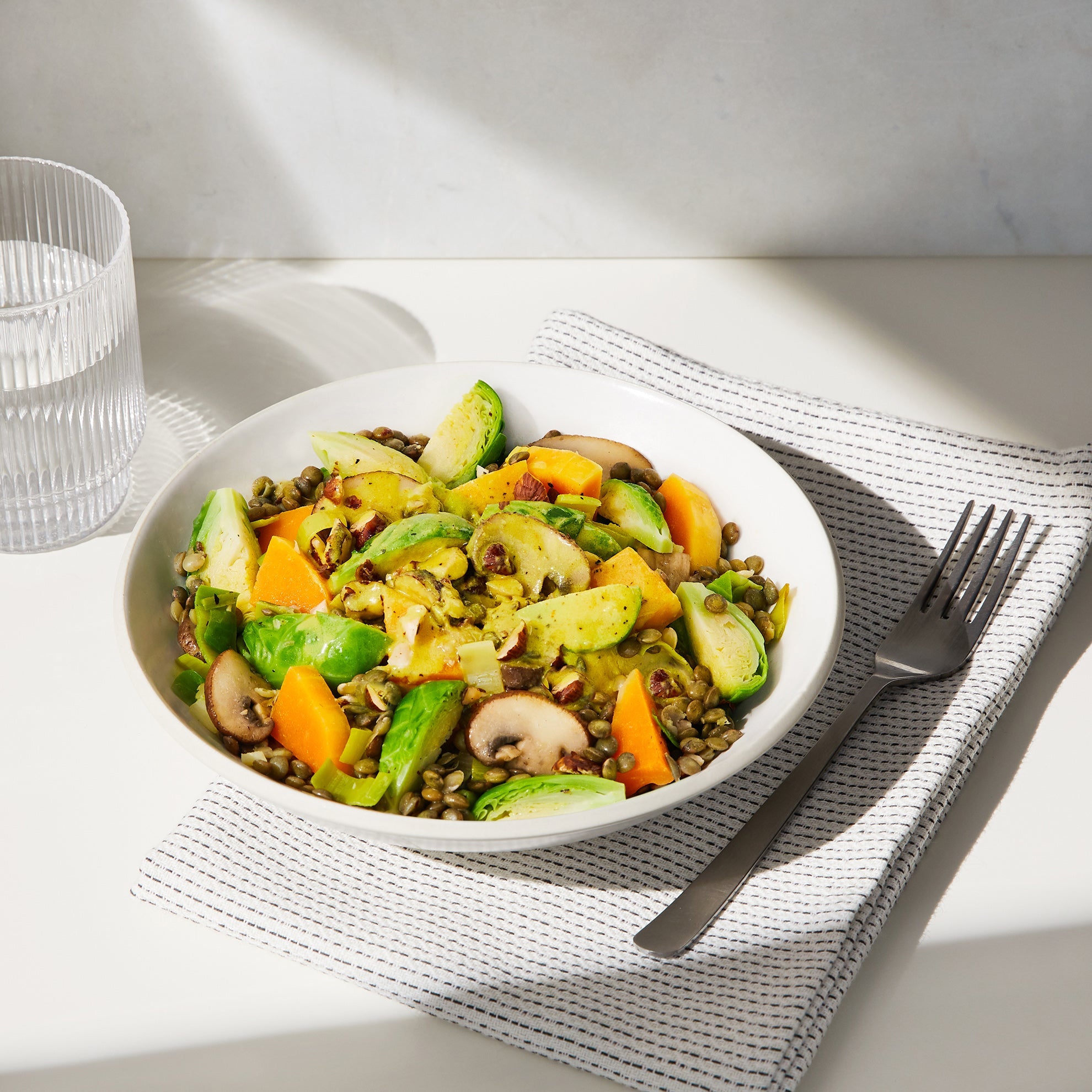 A lifestyle image of a prepared Daily Harvest Brussels Sprouts + Tahini Harvest Bowl with garnish.