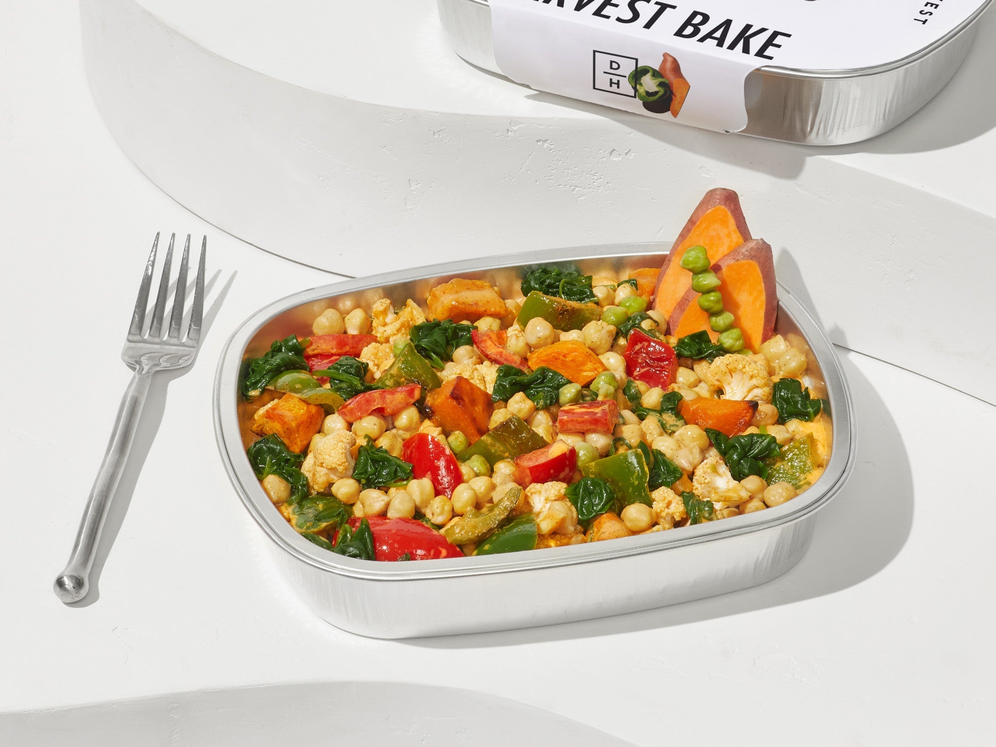 Image of a coconut curry harvest bake sitting in a aluminium container with a fork.