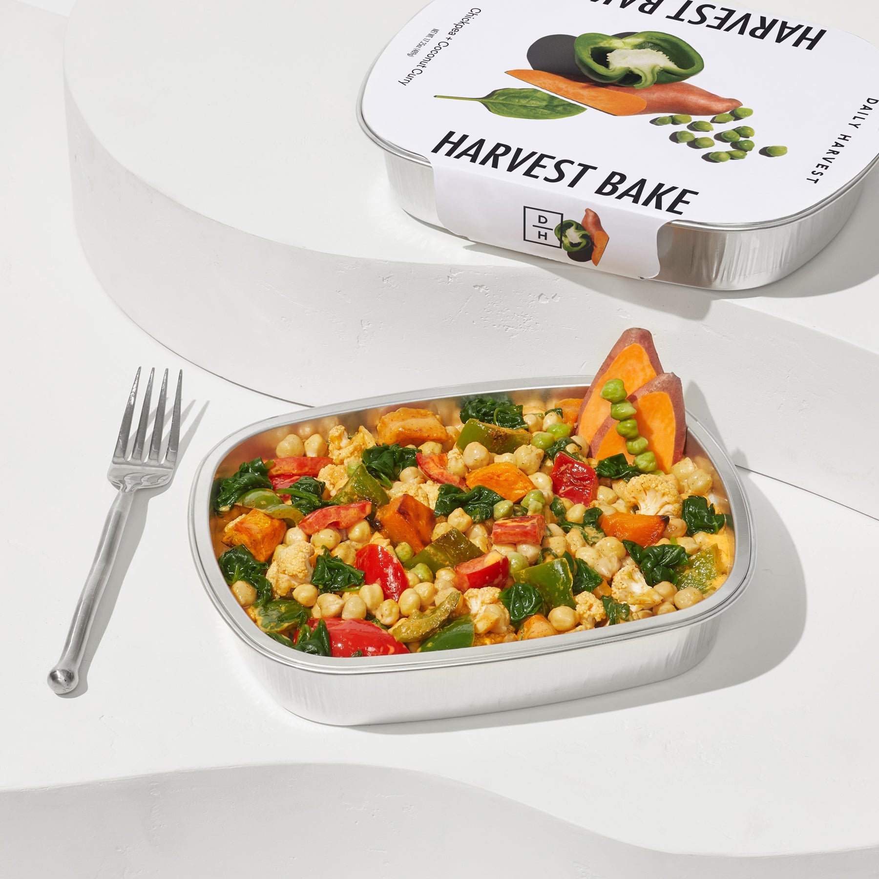 Image of a coconut curry harvest bake sitting in a aluminium container with a fork.