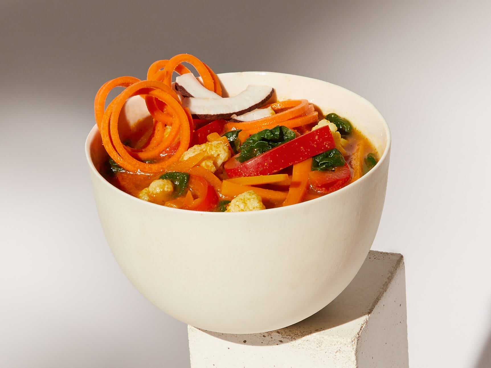 Image of a prepared Daily Harvest Carrot + Coconut Soup in a bowl with garnish.