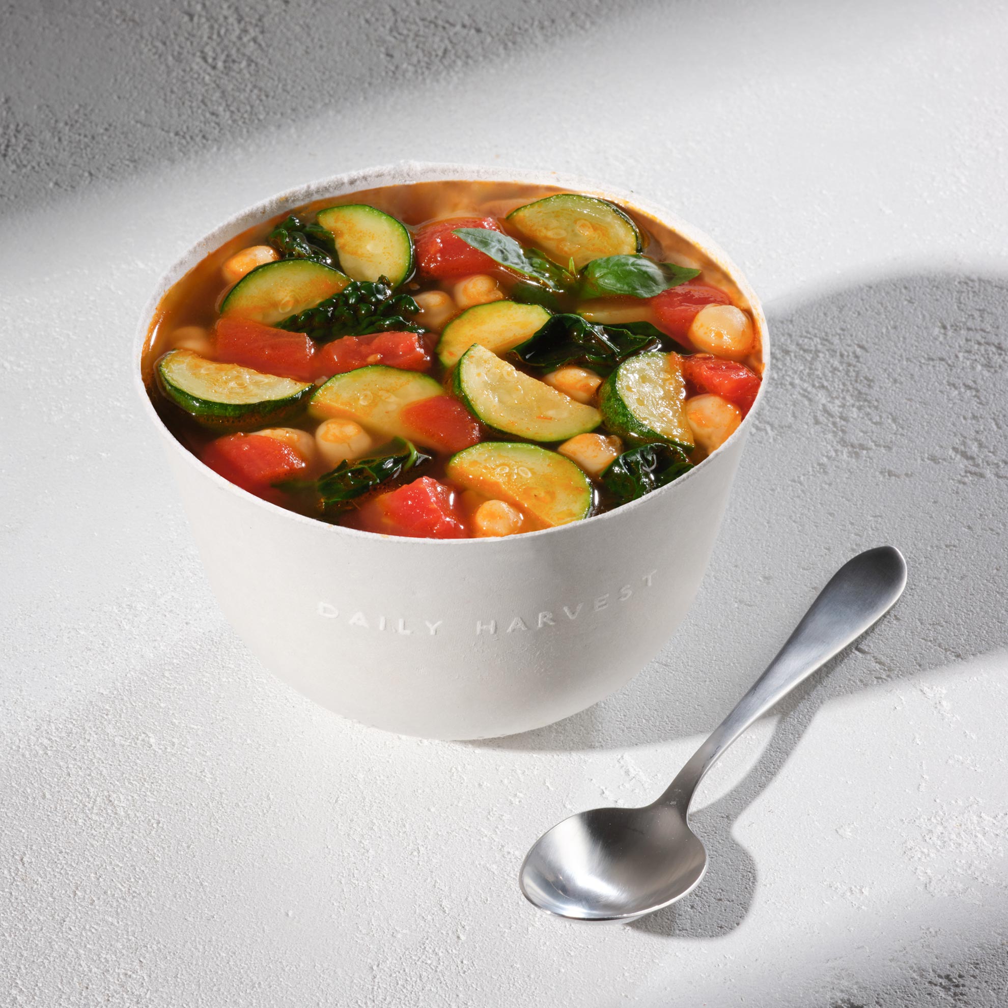 Lifestyle Image of Daily Harvest Tomato + Zucchini Minestrone Soup prepared in a bowl.