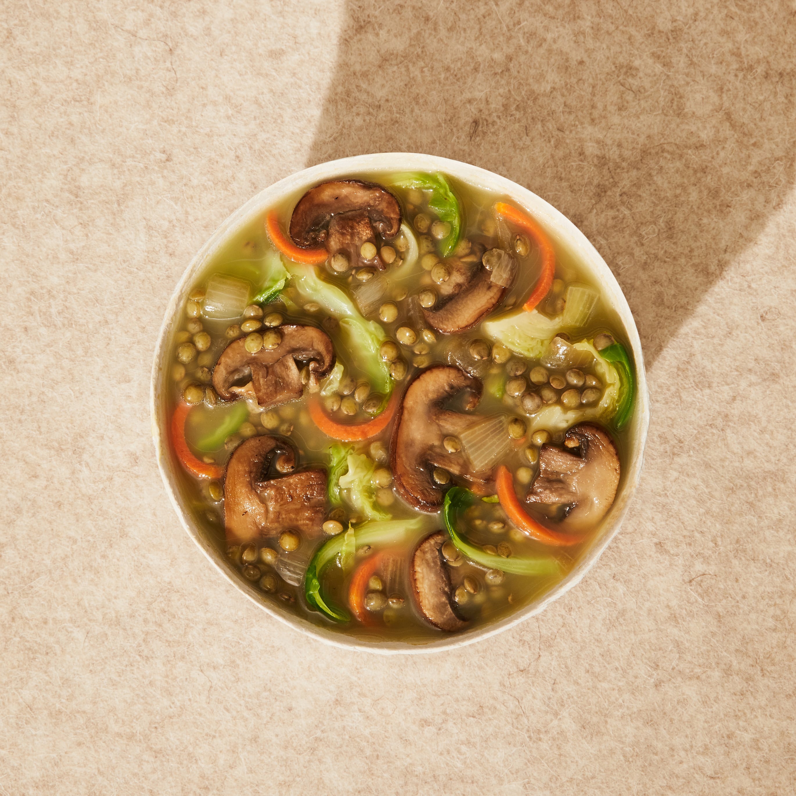 A close up lifestyle image of Daily Harvest Lentil + Cremini Soup prepared in a bowl.