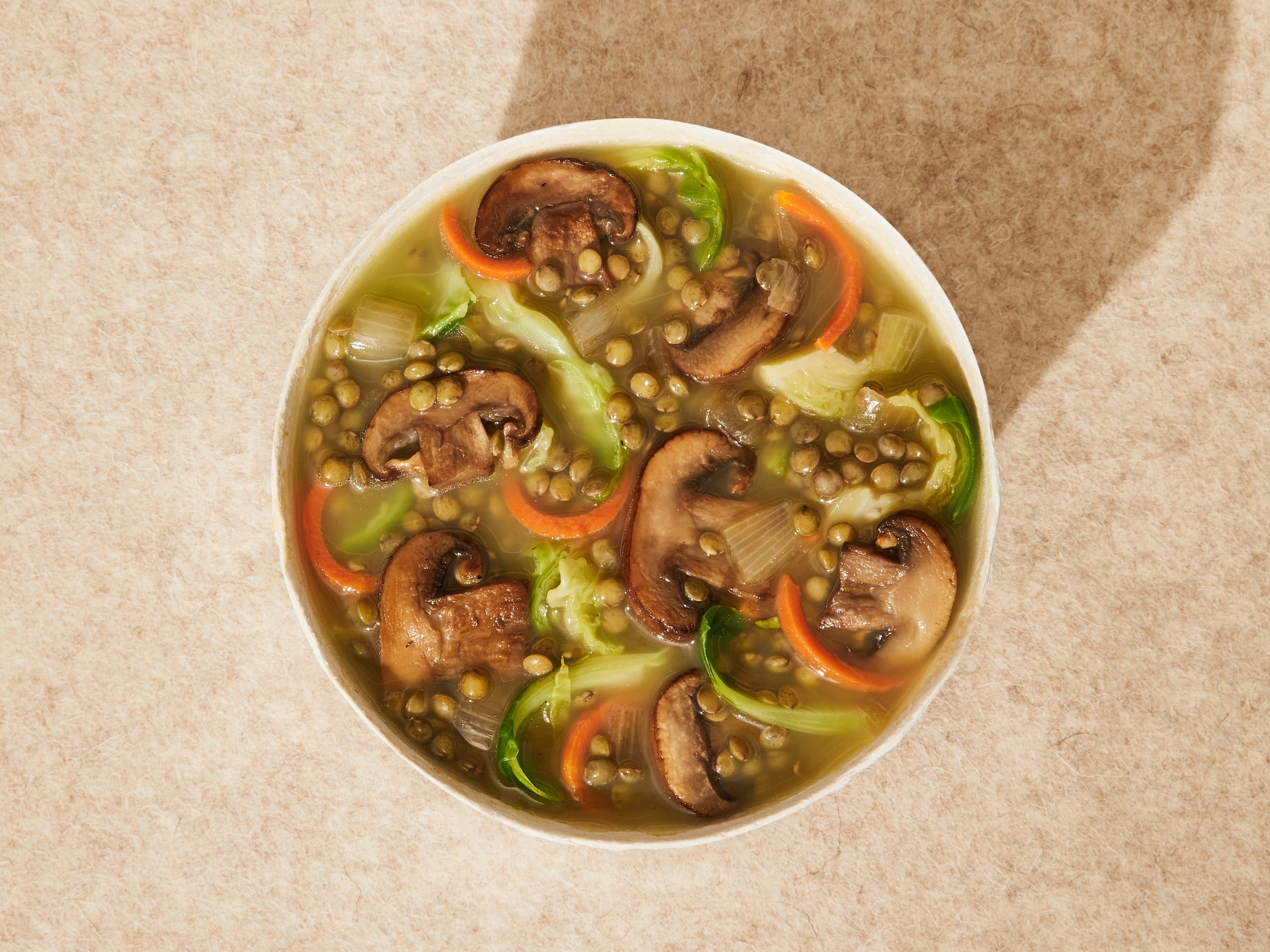 A close up lifestyle image of Daily Harvest Lentil + Cremini Soup prepared in a bowl.