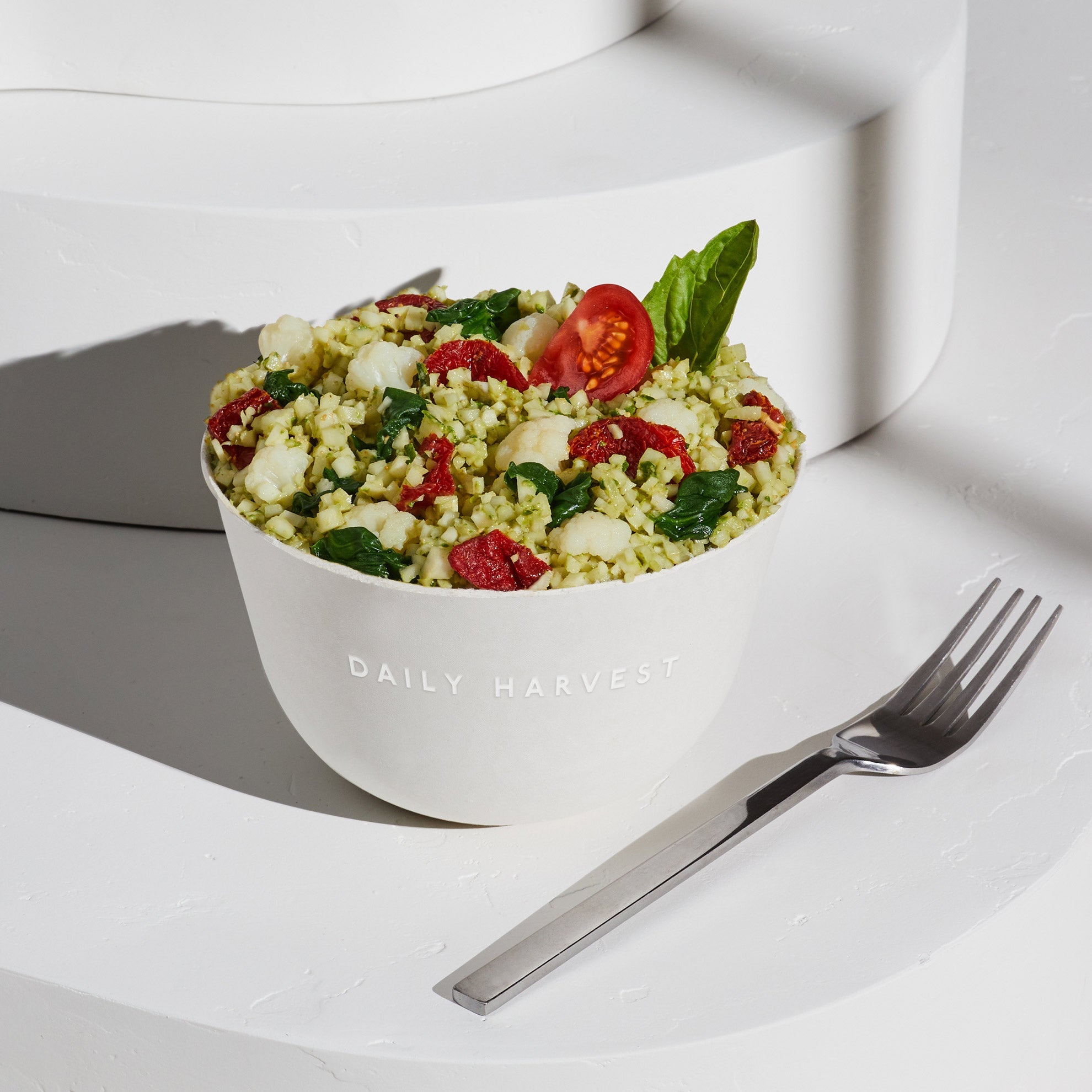 Lifestyle image of a prepared Cauliflower Rice + Pesto Harvest Bowl with an added garnish.