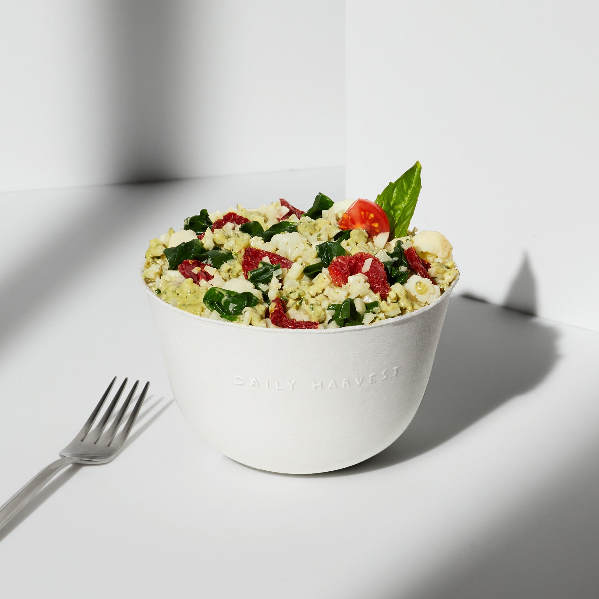 Lifestyle image of a prepared Cauliflower Rice + Pesto Harvest Bowl with an added garnish.