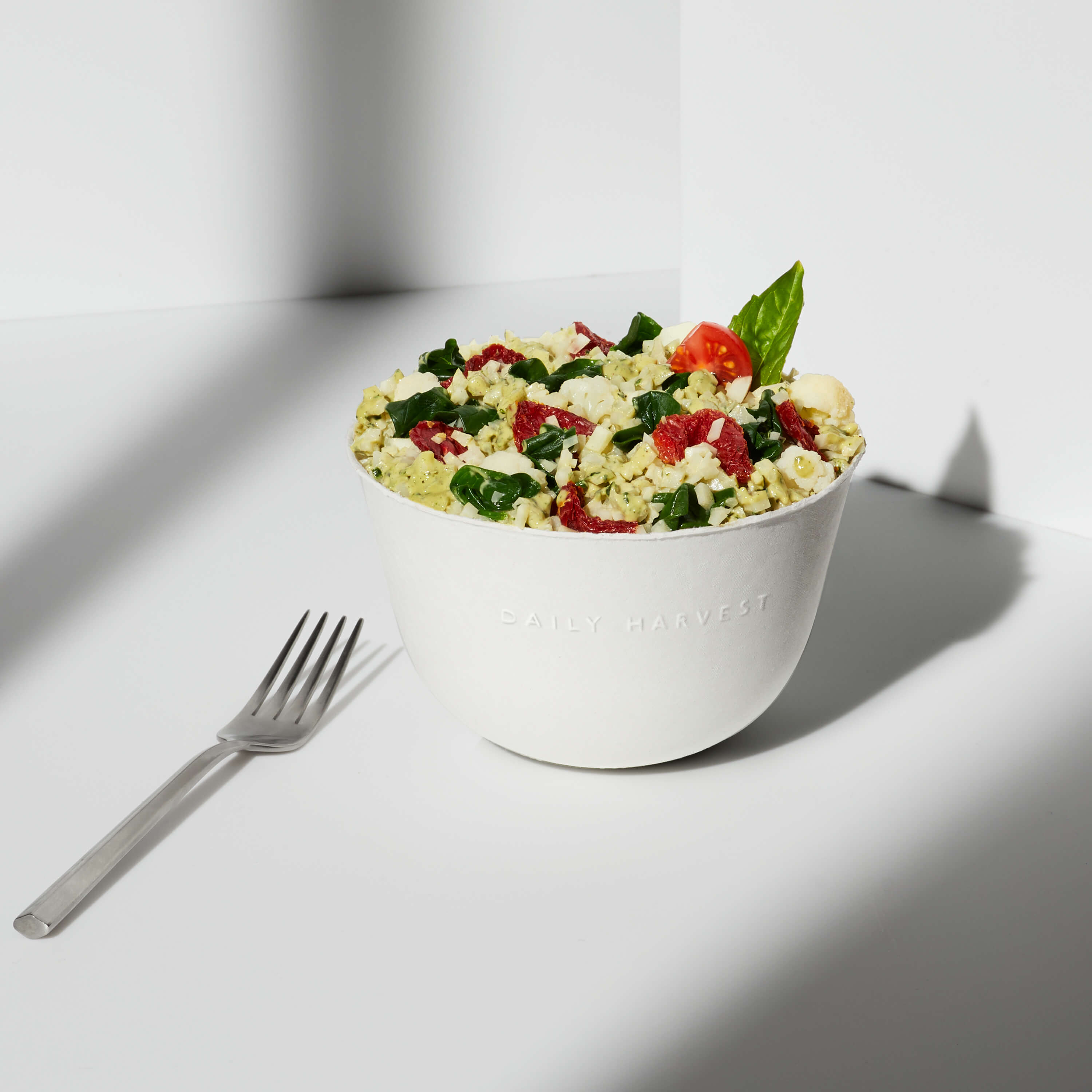 Lifestyle image of a prepared Cauliflower Rice + Pesto Harvest Bowl with an added garnish.