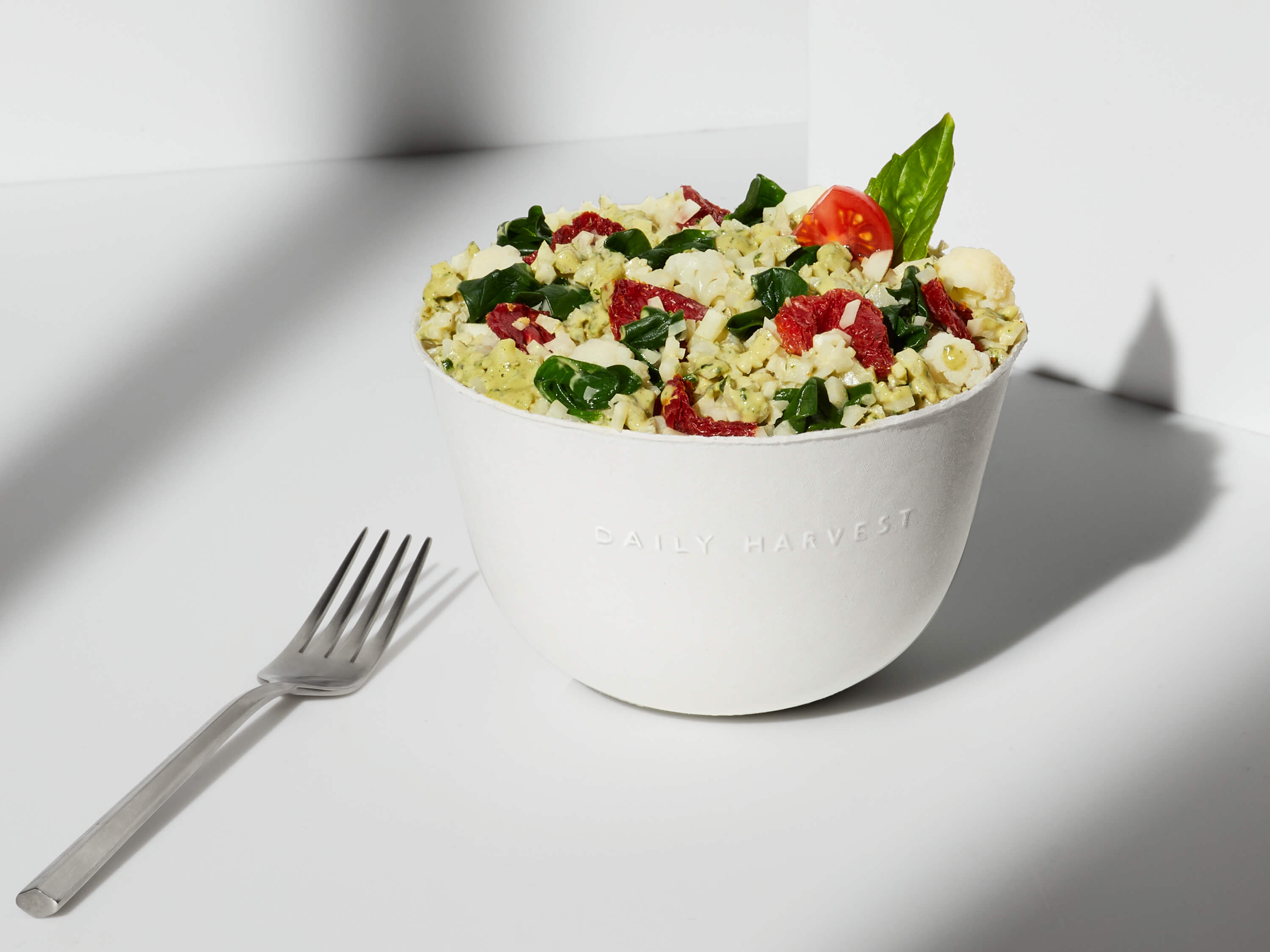 Lifestyle image of a prepared Cauliflower Rice + Pesto Harvest Bowl with an added garnish.