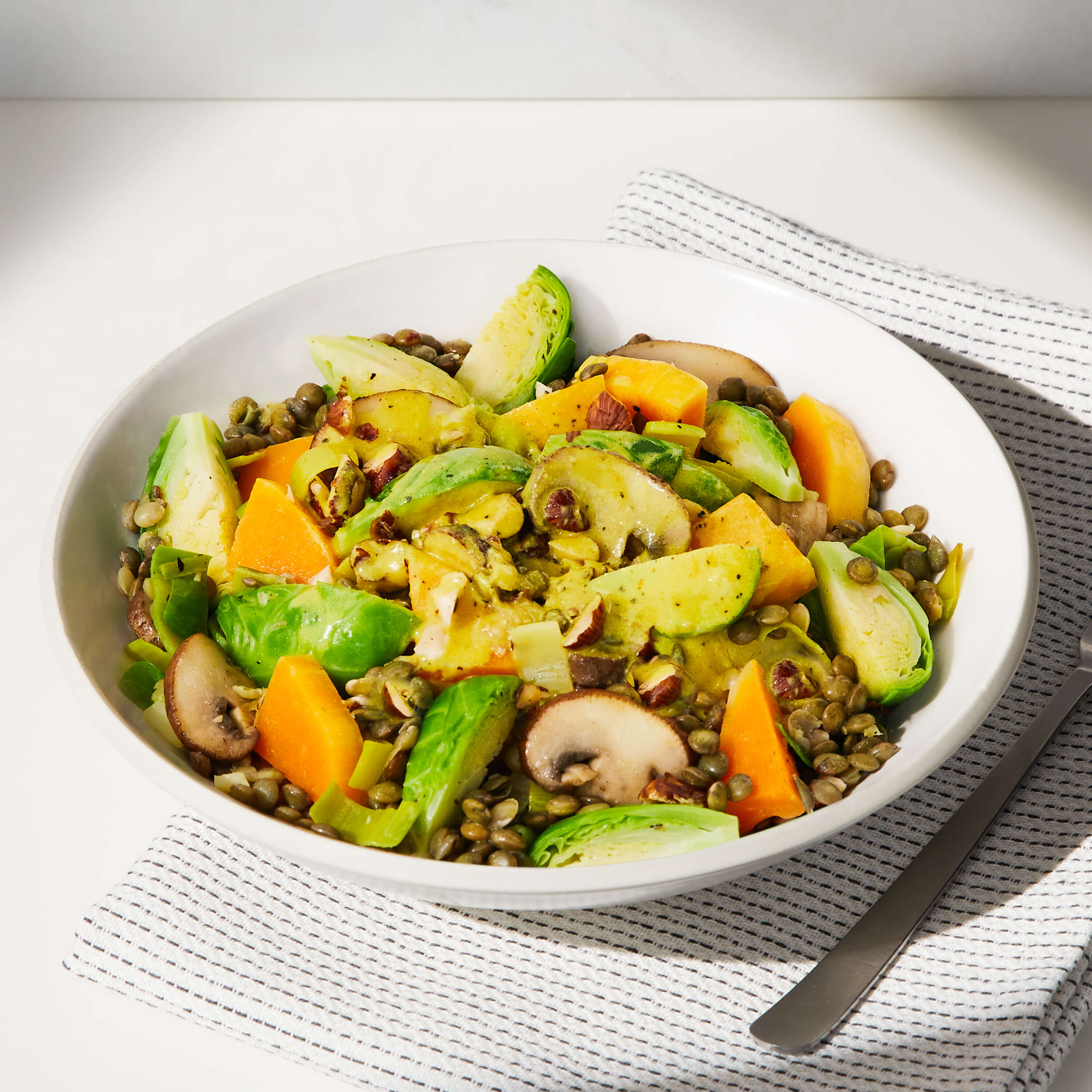 A lifestyle image of a prepared Daily Harvest Brussels Sprouts + Tahini Harvest Bowl.