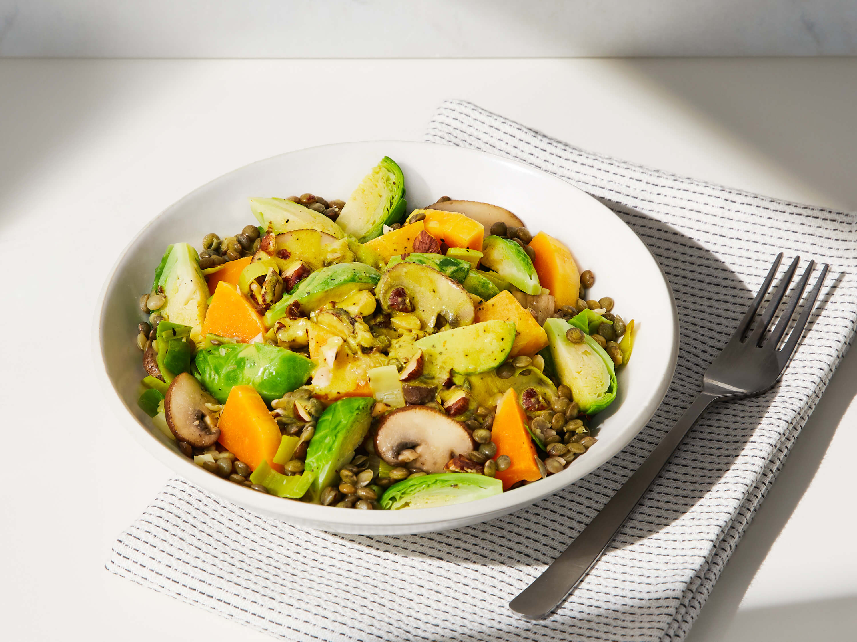 A lifestyle image of a prepared Daily Harvest Brussels Sprouts + Tahini Harvest Bowl.