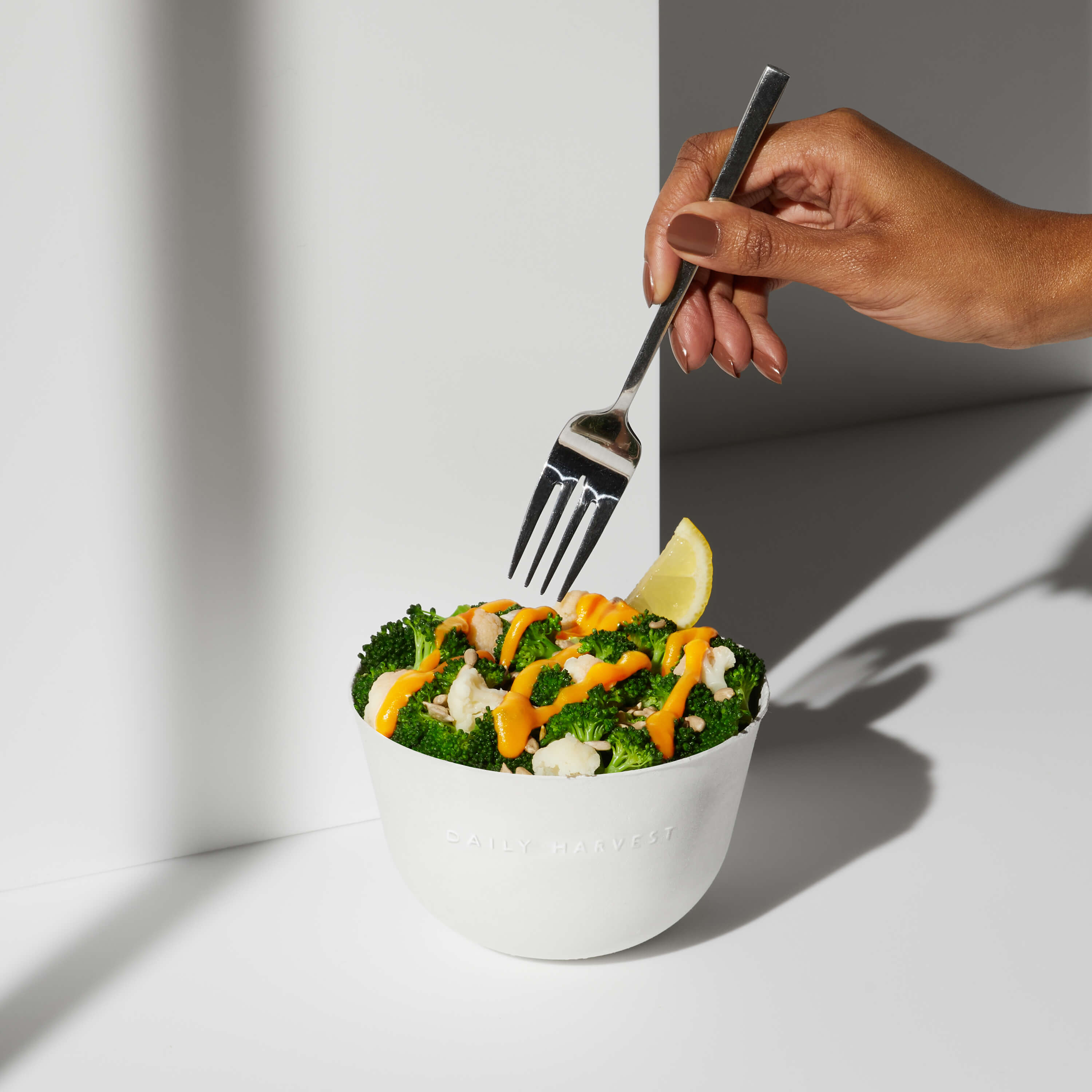 A hand with a fork reaching for a bite of the Broccoli + Cheeze Harvest Bowl