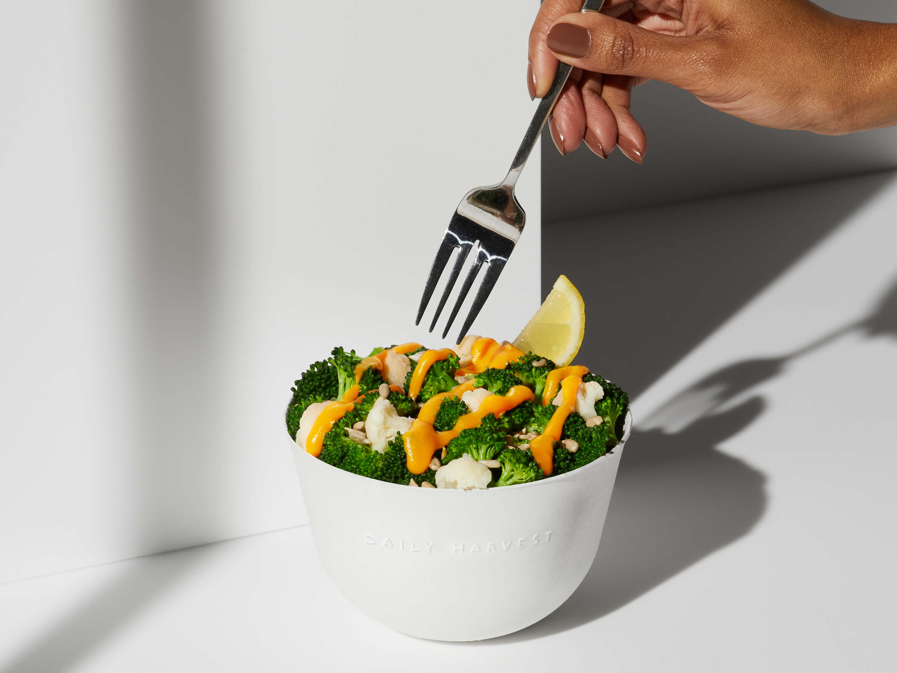 A hand with a fork reaching for a bite of the Broccoli + Cheeze Harvest Bowl 