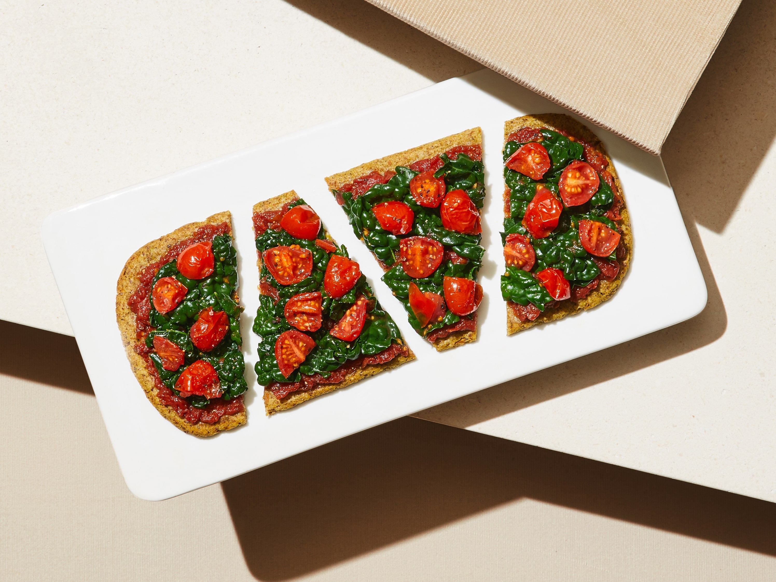 A sliced and prepared Tomato + Basil Flatbread on a plate